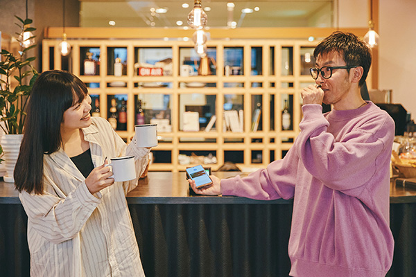 ヤタガイにタッチ決済の使用感を伝えているハナサキ