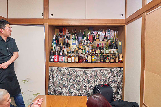 押入れの中に立ち並ぶたくさんの焼酎やウイスキー