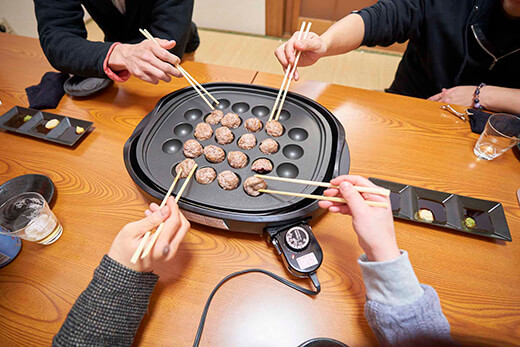 ひき肉をたこ焼き機に押し当てながら仕上げ焼きをする