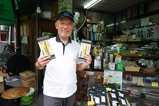 ”世界農業遺産”のお茶を掲げる矢嶋さん。